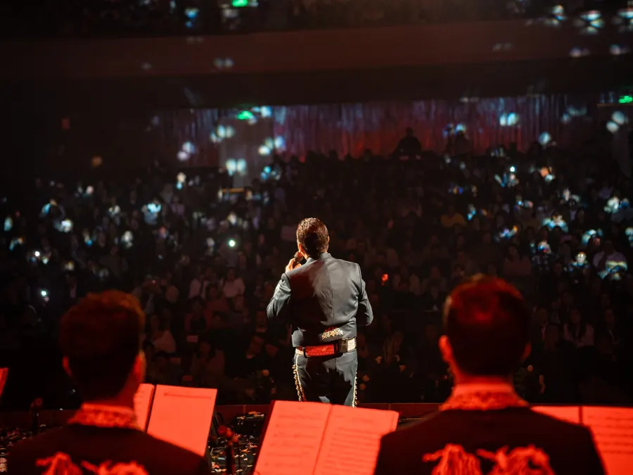 Público iluminando el teatro con sus celulares durante un concierto de Mariachi Tabasco